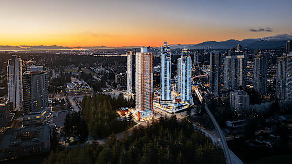 A cityscape at dusk with tall buildings and a river running through it.
