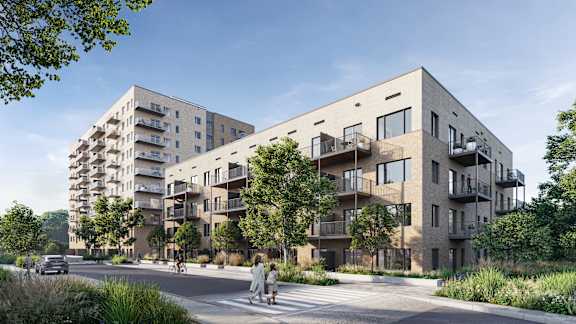 A modern apartment building with balconies and a person walking on the sidewalk.