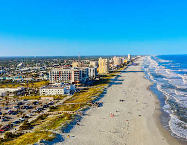 A beach with waves coming in and buildings in the background.