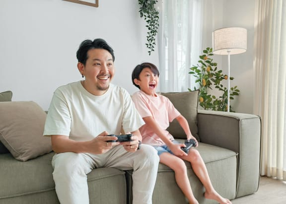 a man and a child sitting on a couch playing video games