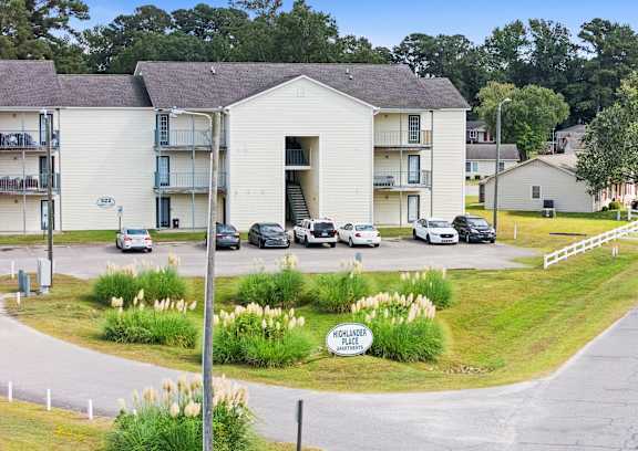 A white building with a sign that says "Hillcrest Apartments" in front of it.
