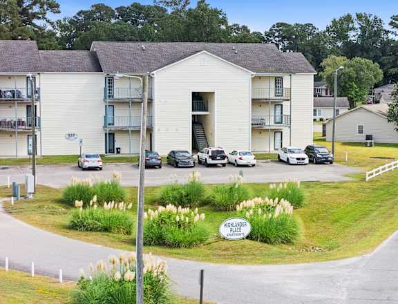 A white building with a sign that says "Hillcrest Apartments" in front of it.