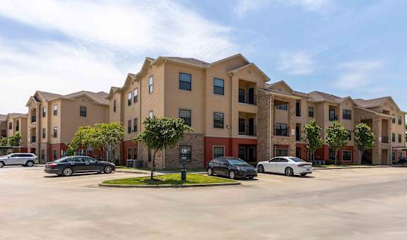 Sugar Mill Apartments in Addis, LA photo of a large apartment building with cars parked in front of it