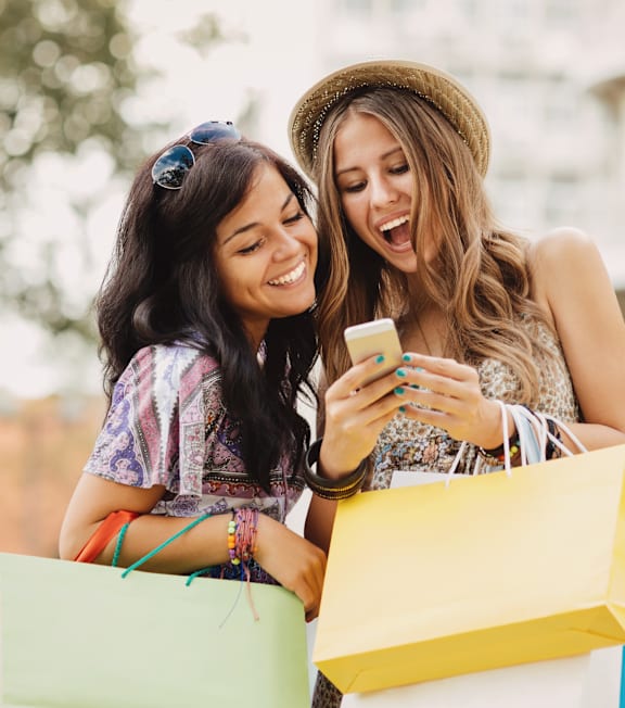 Two women with shopping bags looking at a phone.at The Blvd Lofts, California, 91436