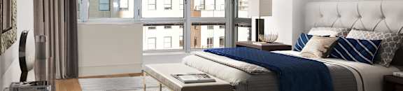 A modern bedroom with a large bed and a view of the city.at 'The Metropolis', New York, 10017