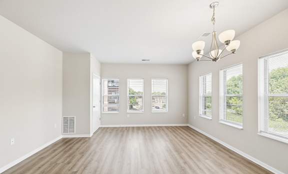 A large, empty room with wooden floors and a chandelier.