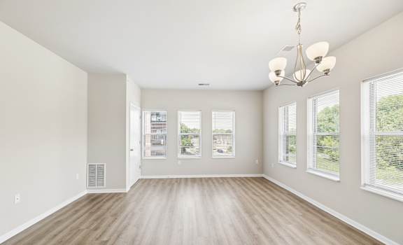 A large, empty room with wooden floors and a chandelier.
