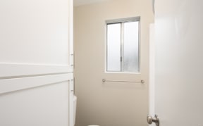 A white toilet sits in a bathroom with a door and a window.