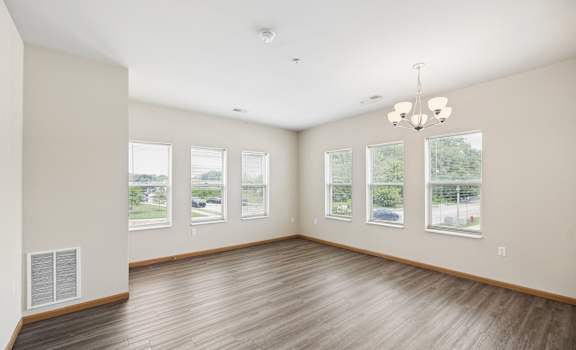 A large empty room with wooden floors and a chandelier.