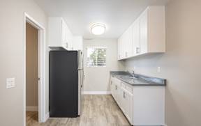 A kitchen with a black refrigerator and white cabinets.