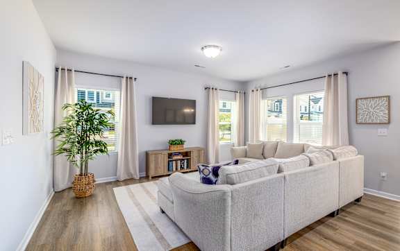 A living room with a large couch and a flat screen TV mounted on the wall.
