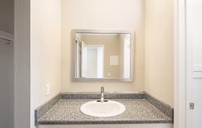 A bathroom sink with a granite counter top and a mirror above it.