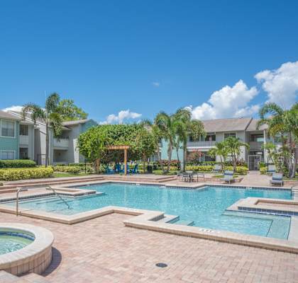 a large swimming pool with a jacuzzi in front of an apartment building