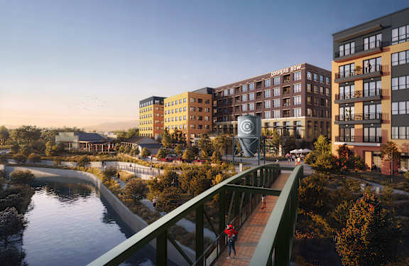 A pedestrian is walking on a bridge over a river in a city.