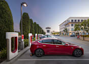 Thumbnail 3 of 13 - A red Tesla car is parked at a charging station.