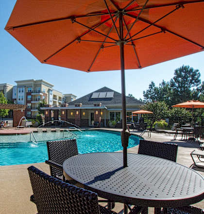 A patio with a table and chairs under an orange umbrella.