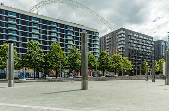 A large open plaza with trees and buildings in the background at Beton Apartments, Wembley, HA9 0SL