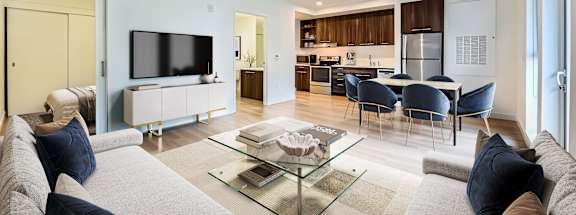 A modern living room with a grey sofa and a glass coffee table.