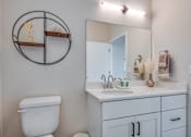 Thumbnail 19 of 22 - A bathroom with a toilet, sink, and mirror.