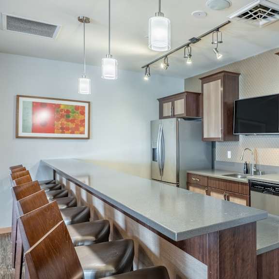 A gray and brown clubhouse with tables and chairs and a kitchen at Vue at Pinnacle Park.
