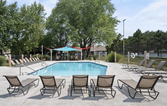 a swimming pool with chaise lounge chairs and trees in the background