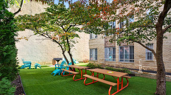 A red picnic table is in the middle of a grassy area.