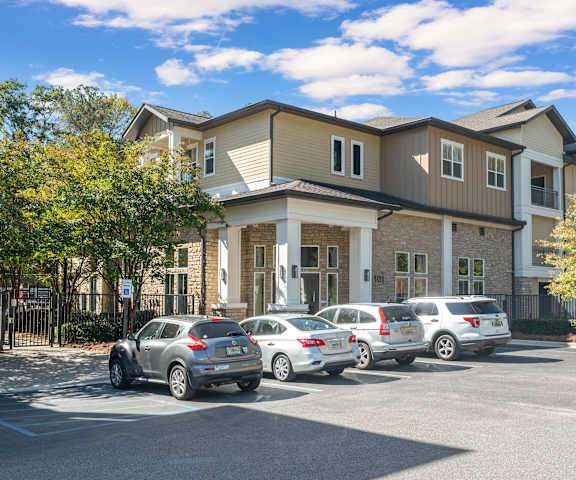 A row of cars are parked in front of a building.