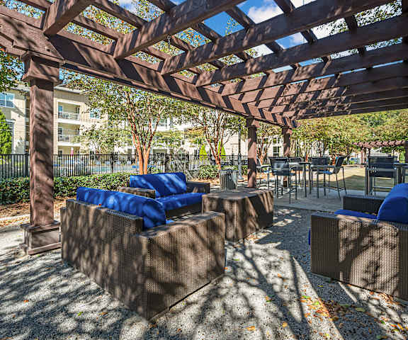 A wooden pergola with blue cushions and a concrete floor.