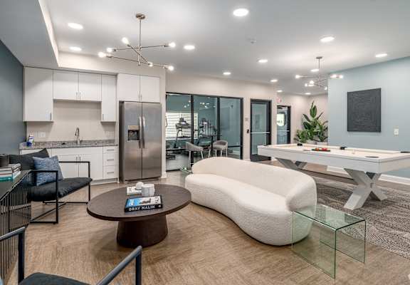 A modern kitchen with a breakfast bar and a living room area with a sofa and a coffee table. at Park Lamont Apartments & Townhomes, Ohio