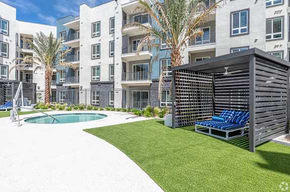 A modern apartment complex with a pool and a sun lounger.