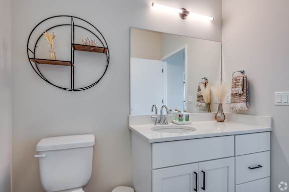 A bathroom with a toilet, sink, and mirror.