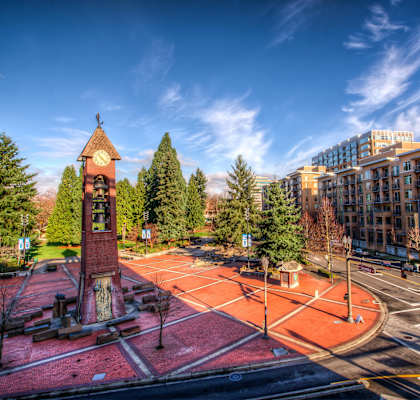 A clock tower stands in the middle of a courtyard.