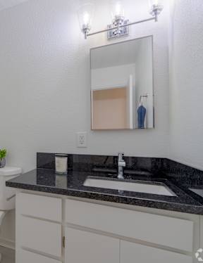 A bathroom with a white toilet, a sink, and a mirror.