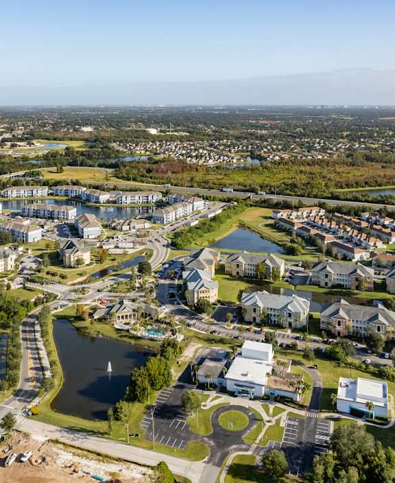 A bird's eye view of a residential area with a lake and a road.
