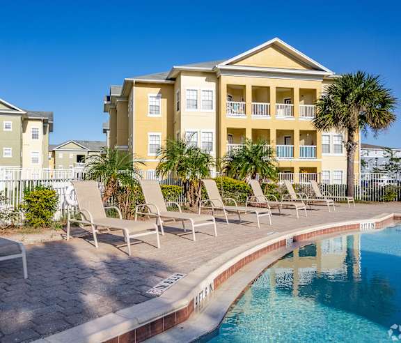 A pool area with chairs and a building in the background.