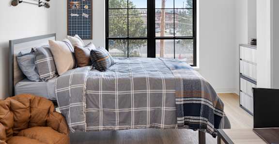A bedroom with a bed, a chair, and a window with a view of the city.