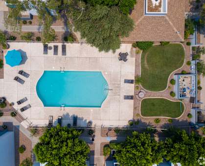 An aerial view of a swimming pool surrounded by trees and buildings. at Sycamore Square  Apartments, Arizona, 85202