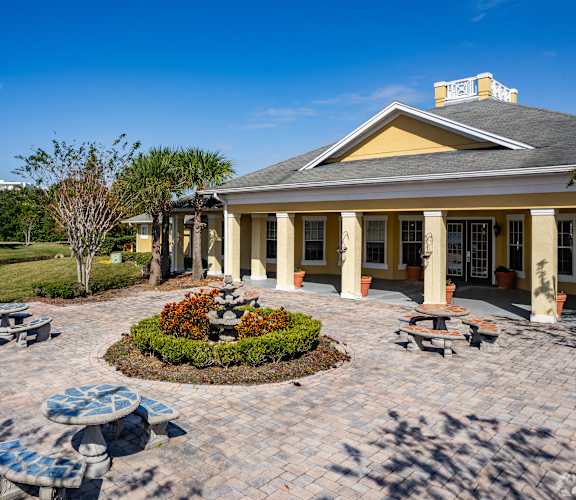 A building with a yellow roof and columns is surrounded by a circular garden with benches.