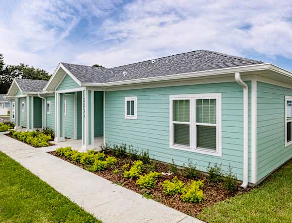 a row of blue houses with a sidewalk in front of them