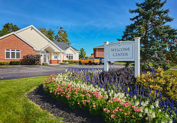 the welcome center sign in front of a building with flowers at Centerpointe Apartments, Canandaigua