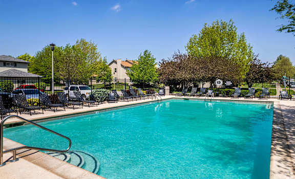 A large swimming pool surrounded by chairs and trees.