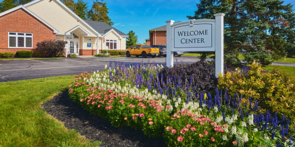 the welcome center sign in front of a building with flowers at Centerpointe Apartments, Canandaigua, 14424