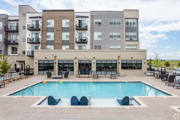 A large swimming pool in front of a multi-story apartment building.