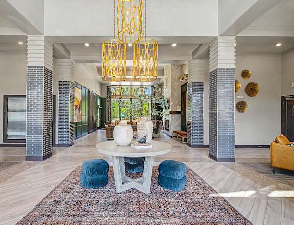 A large white table with blue chairs and a chandelier hangs in a spacious lobby.