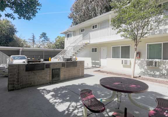 A patio with a table and chairs is in front of a white building.