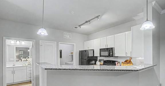 A kitchen with white cabinets and a granite countertop.