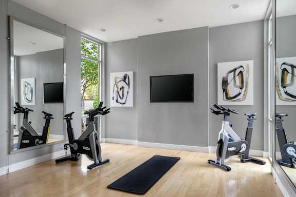 A room with a mirrored wall and exercise bikes.