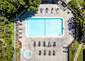 Thumbnail 2 of 11 - An aerial view of a swimming pool surrounded by trees and chairs.