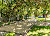 Thumbnail 8 of 11 - A park with a pathway, trees, and a bench.