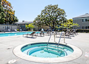 Thumbnail 3 of 11 - A hot tub sits in the middle of a pool surrounded by chairs.